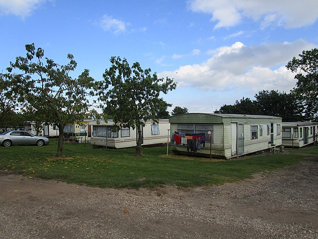 A series of worn-out caravans on a field.